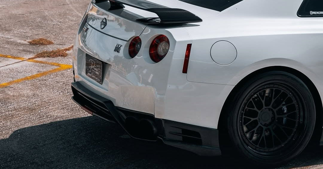 White sports car with black spoiler and rims on a concrete surface