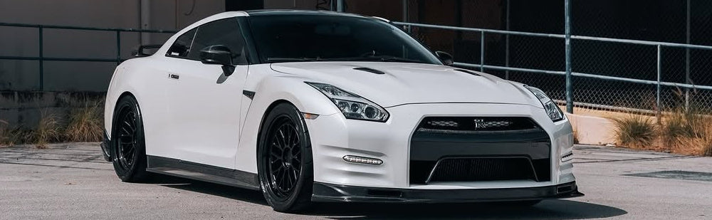 White sports car parked in an industrial area with a building in the background